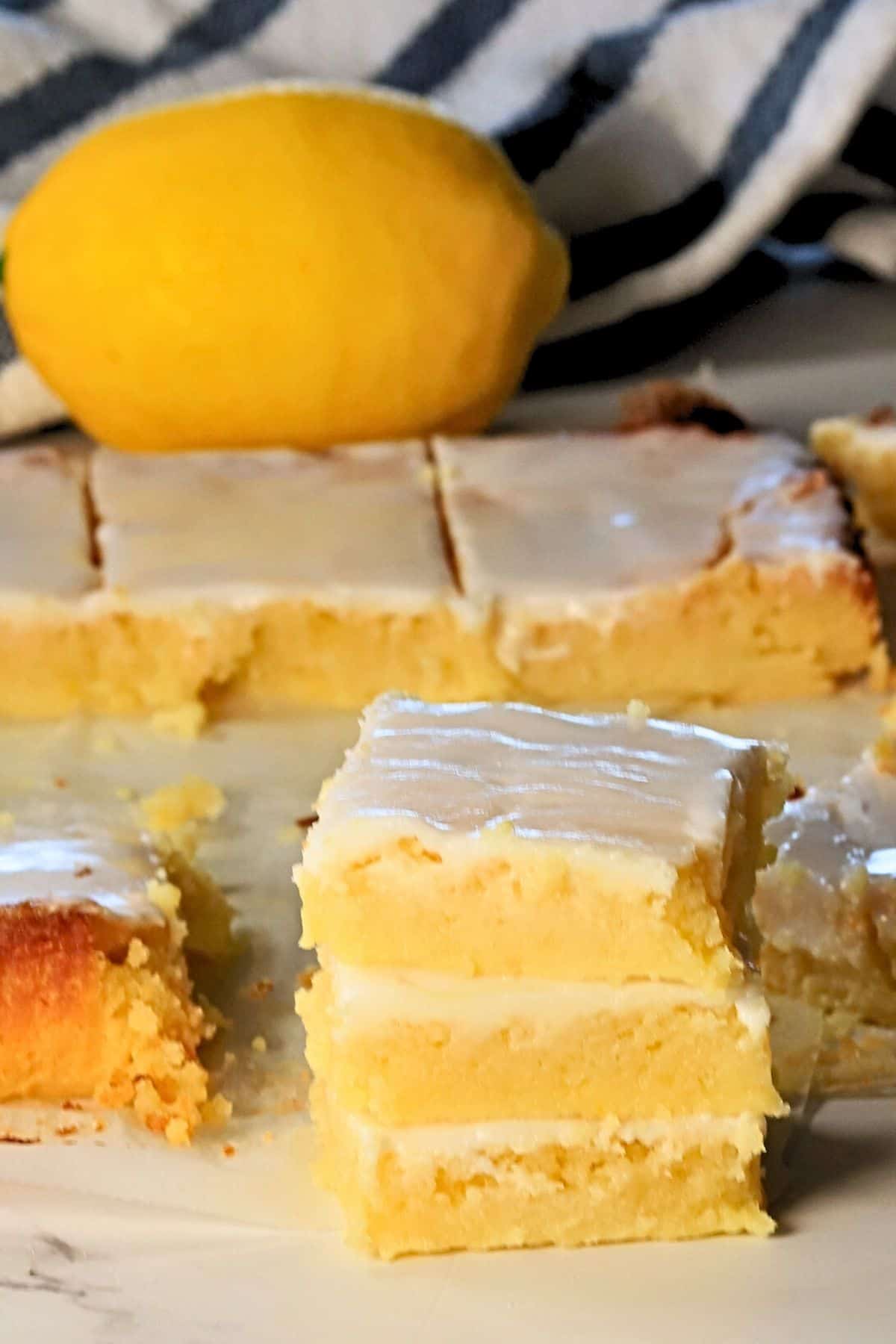Three low carb lemon brownies stacked on top of each other with more behind them.