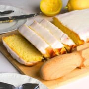 Sugar free lemon loaf slices on a cutting board next to lemons.