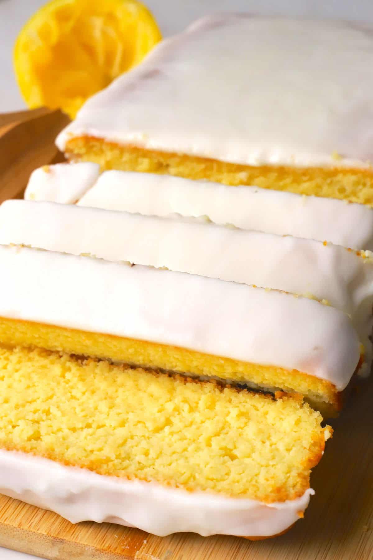 Sugar free lemon loaf slices on a cutting board next to lemons.