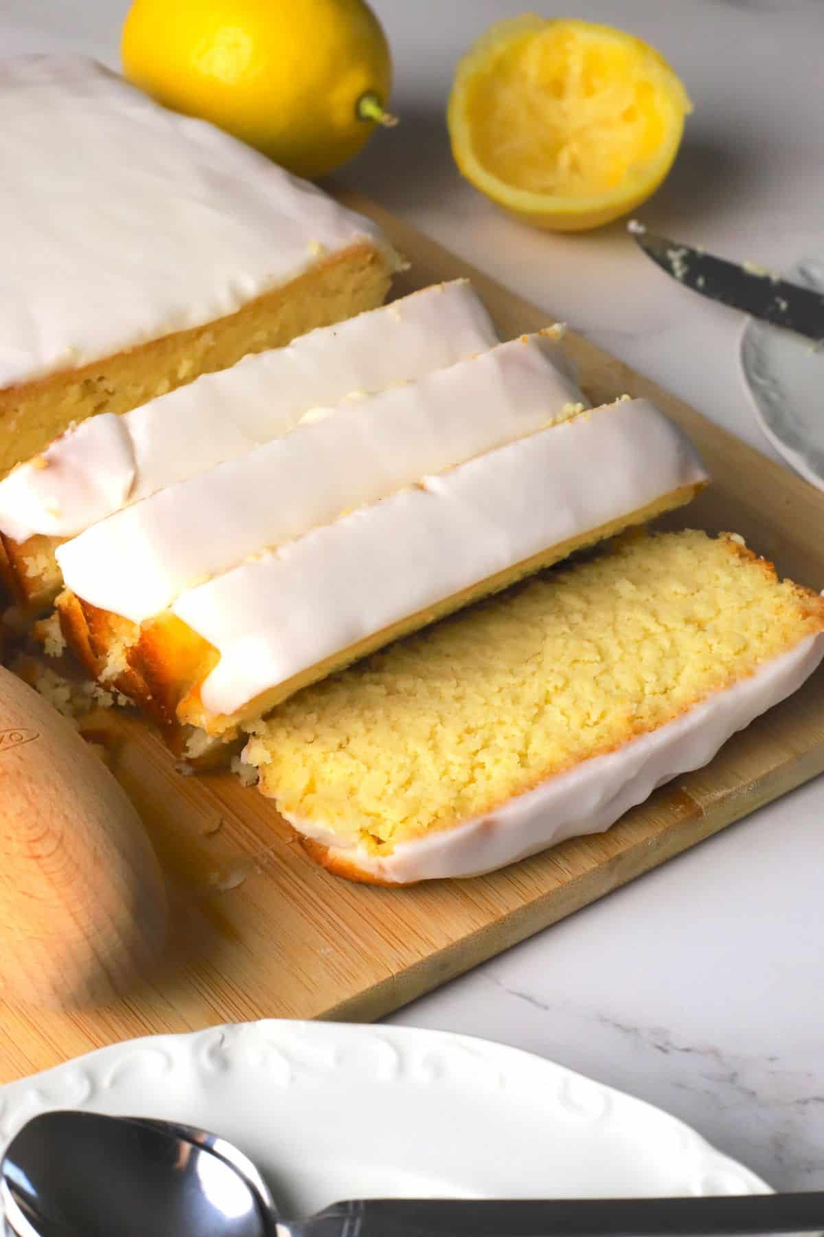 Sugar free lemon loaf slices on a cutting board next to lemons.