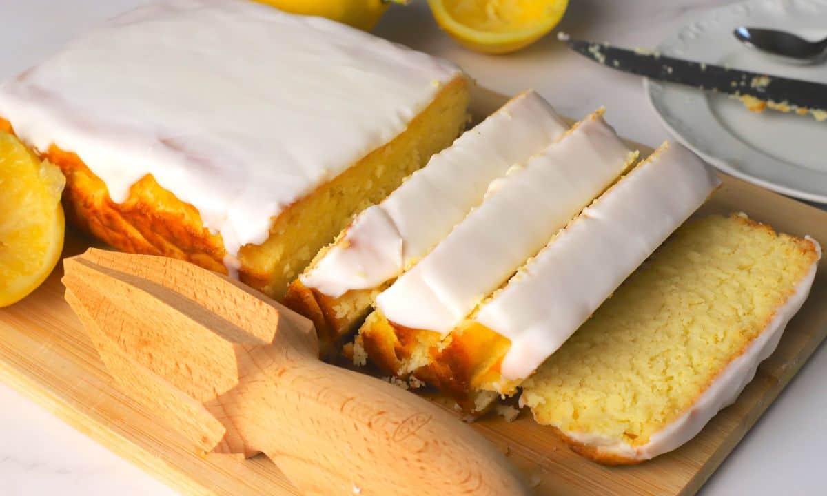 Sugar free lemon loaf slices on a cutting board next to lemons.