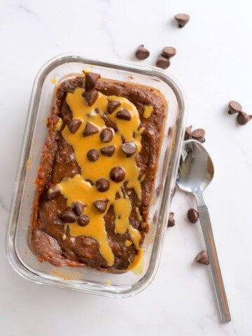 Cottage cheese chocolate protein mug cake drizzled with peanut butter and topped with chocolate chips.