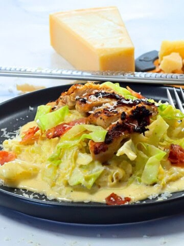 Low carb cabbage alfredo with chicken and bacon on a plate.