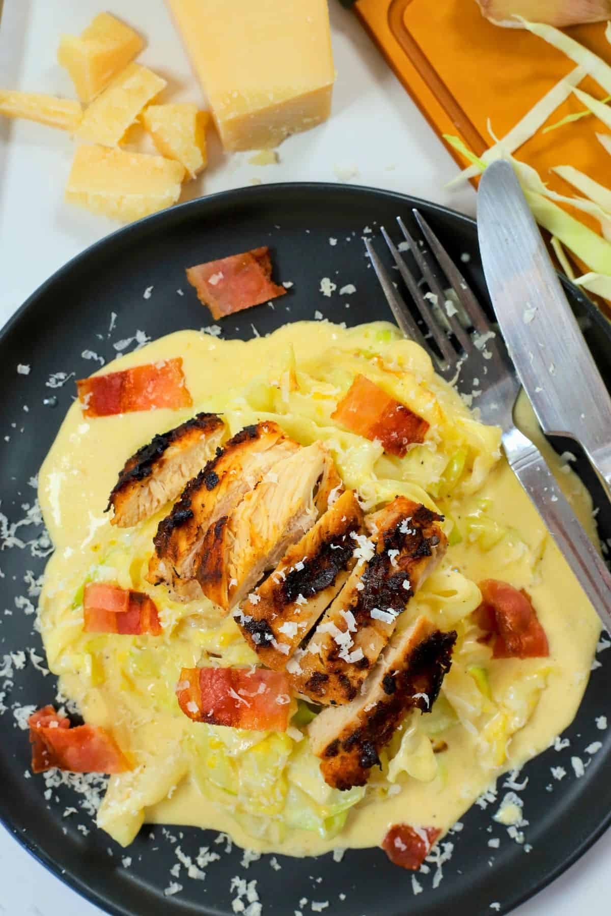 Overhead shot of low carb cabbage alfredo with chicken and bacon on a plate.