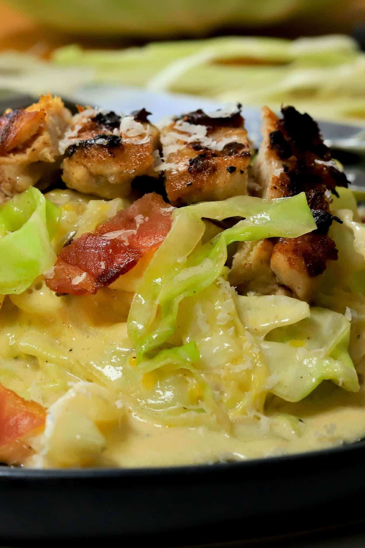 Closeup of low carb cabbage alfredo with chicken and bacon on a plate.