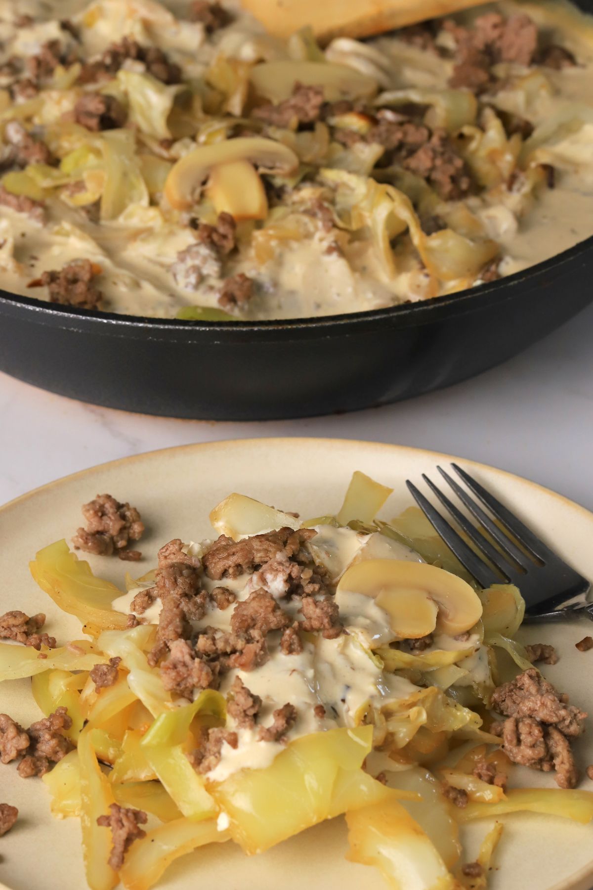 Low carb cabbage beef stroganoff in a skillet next to a plate of the same.