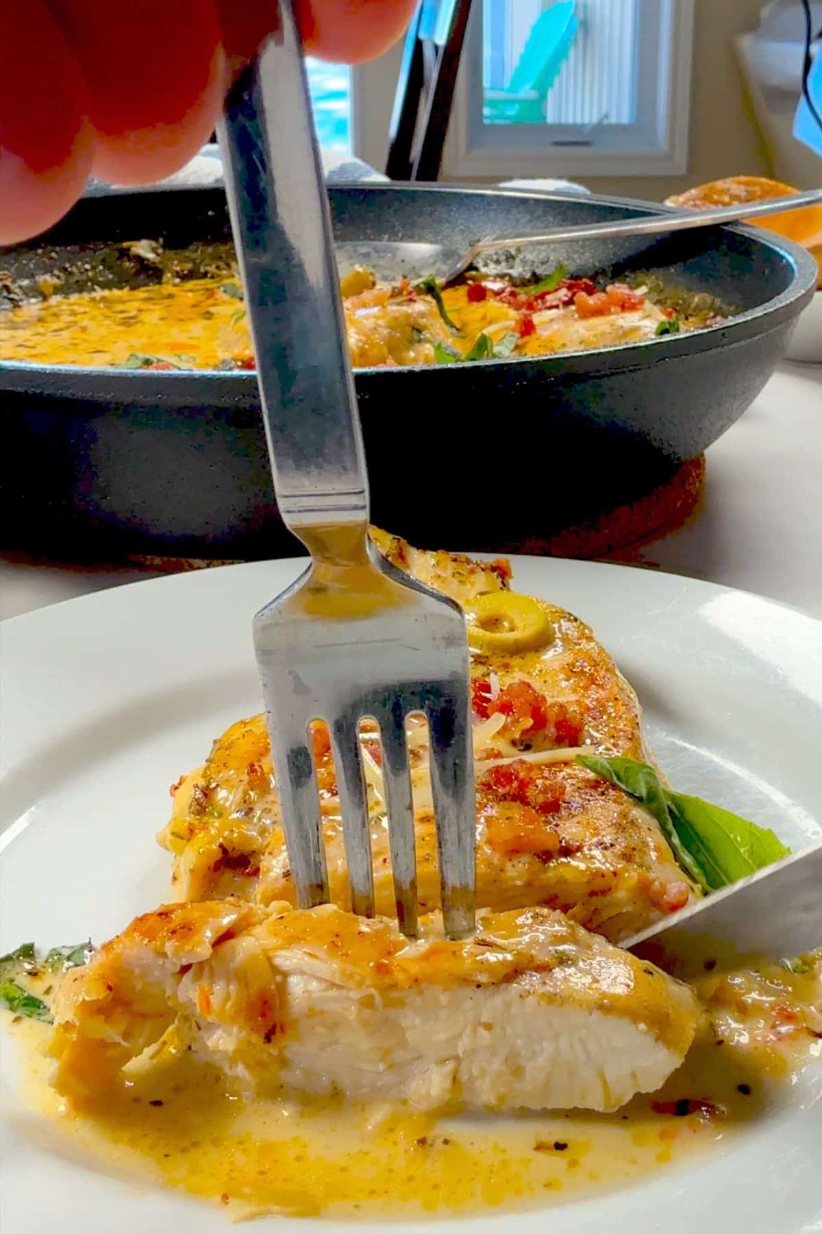 Slicing a piece of low carb marry me chicken on a plate.