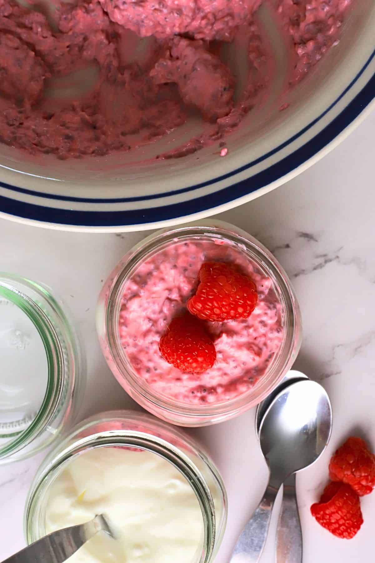 Low carb raspberry chia pudding in a mason jar next to a bowl with the same.