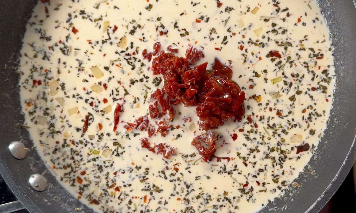 Sauce in a pan with sundried tomatoes in the centre.