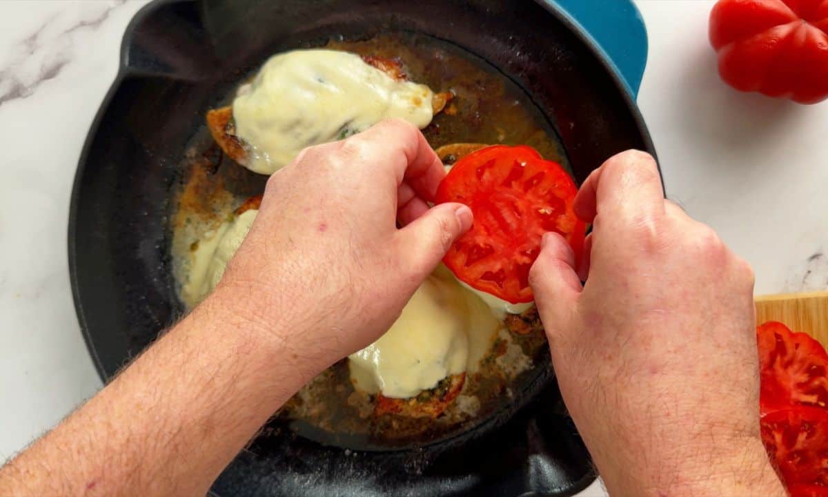 Placing the tomatoe slices on top of the chicken.