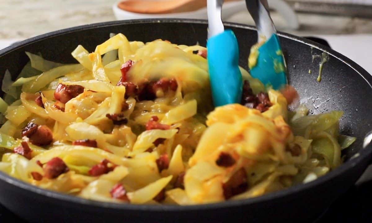 Tossing the cabbage, pancetta and sauce in the pan.
