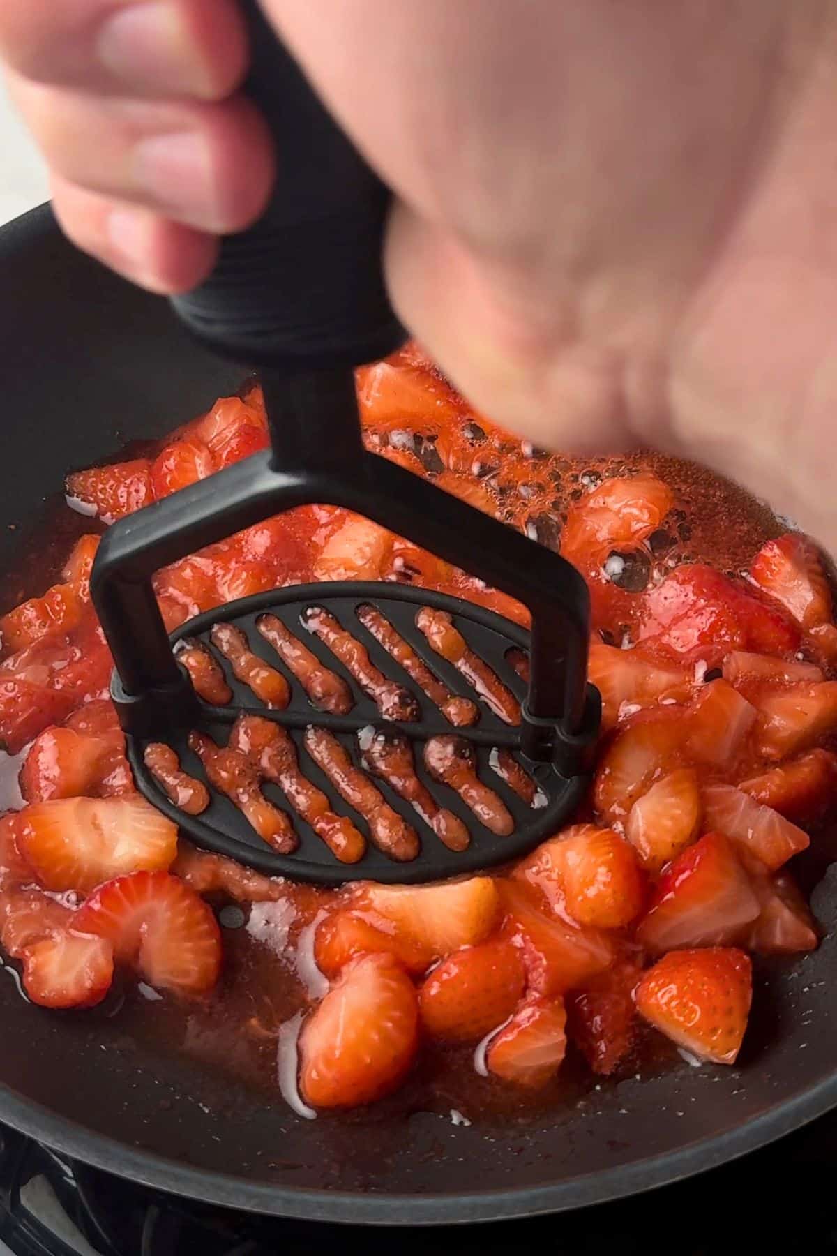 Mashing the strawberries in the pan.