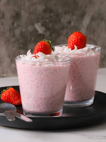 Two cups of low carb strawberry coconut chia pudding topped with strawberries.