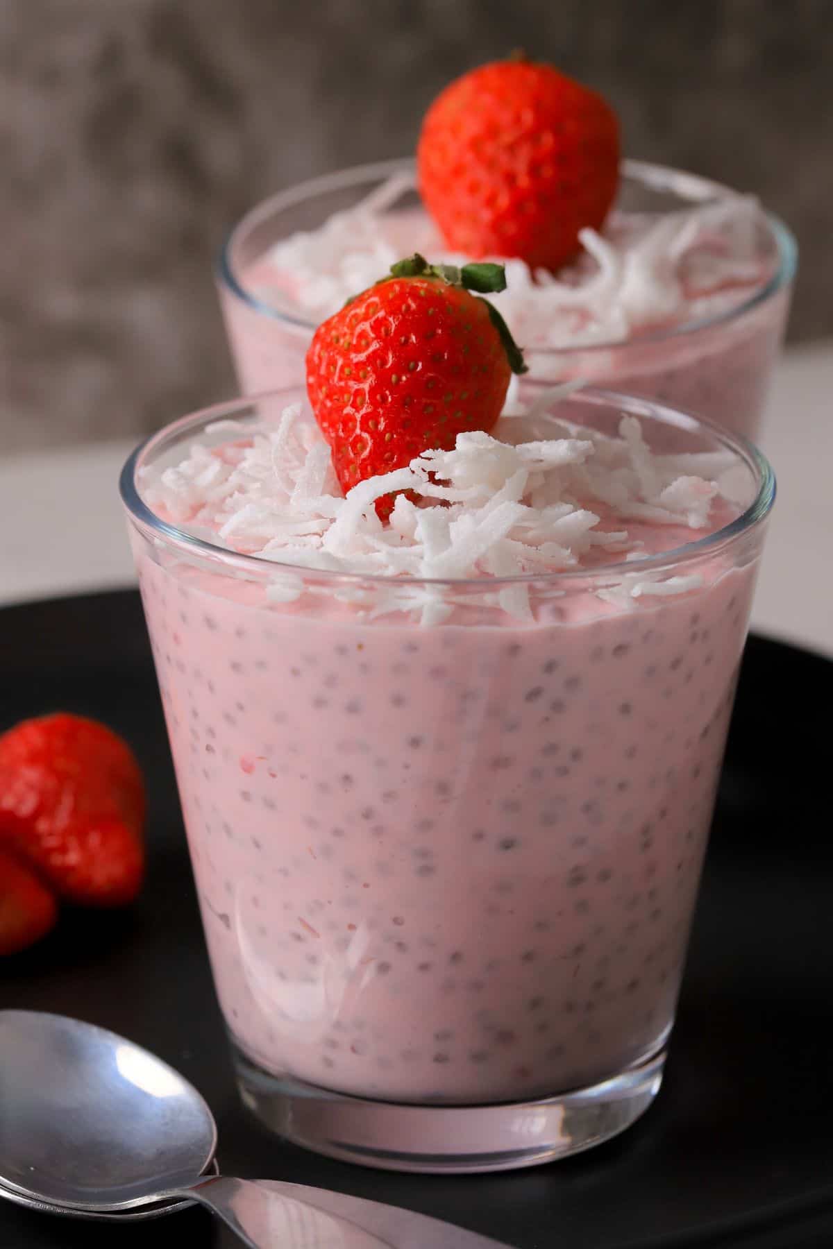 Two cups of low carb strawberry coconut chia pudding topped with strawberries.