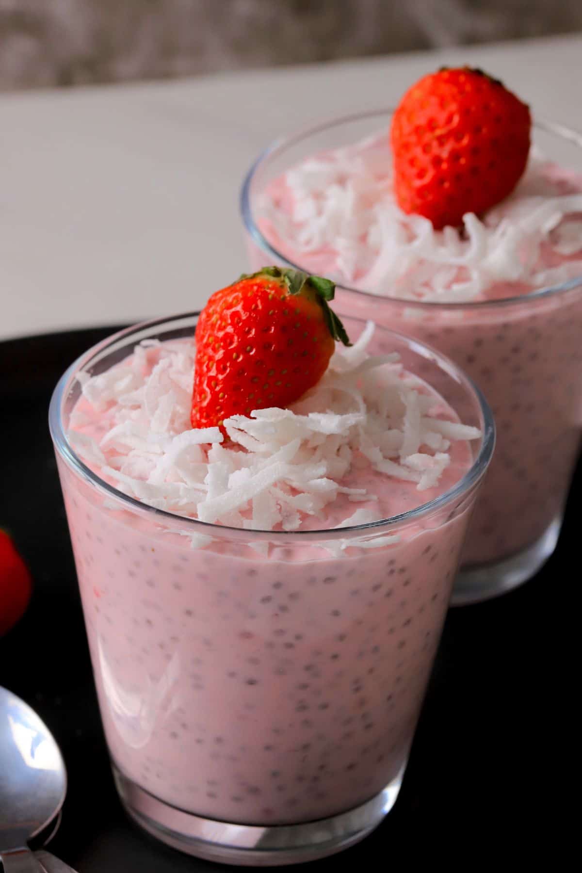 Two cups of low carb strawberry coconut chia pudding topped with strawberries.