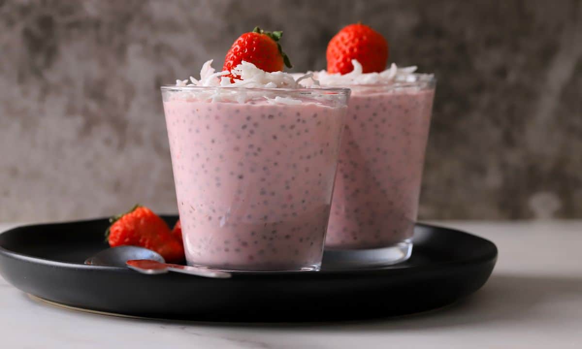 Two cups of low carb strawberry coconut chia pudding topped with strawberries.