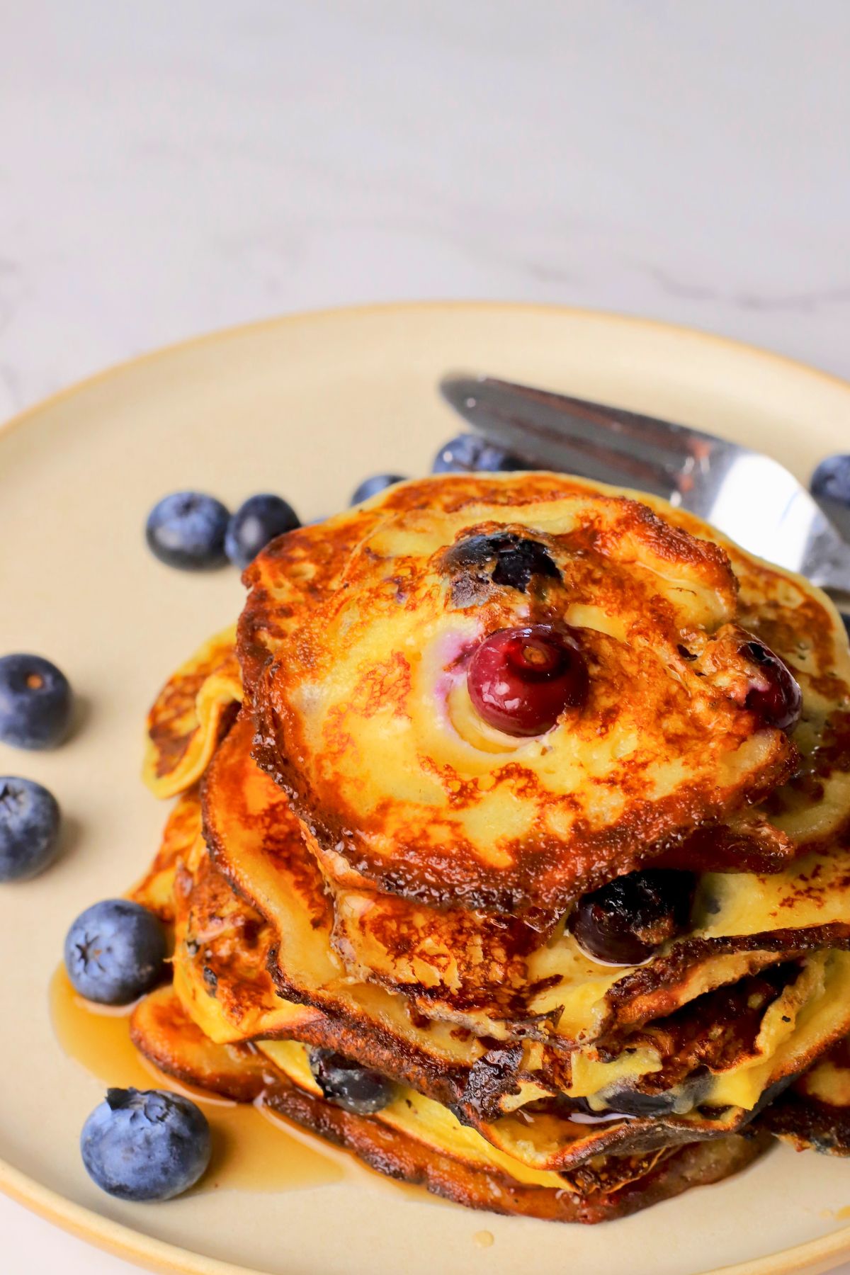 Blueberry cottage cheese pancakes served on a plate with fresh blueberries.