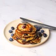Blueberry cottage cheese pancakes served on a plate with fresh blueberries.
