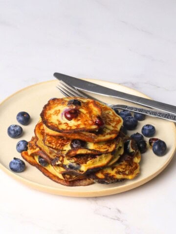 Blueberry cottage cheese pancakes served on a plate with fresh blueberries.