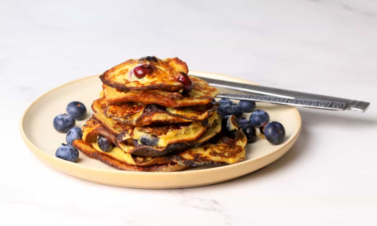 Blueberry cottage cheese pancakes served on a plate with fresh blueberries.