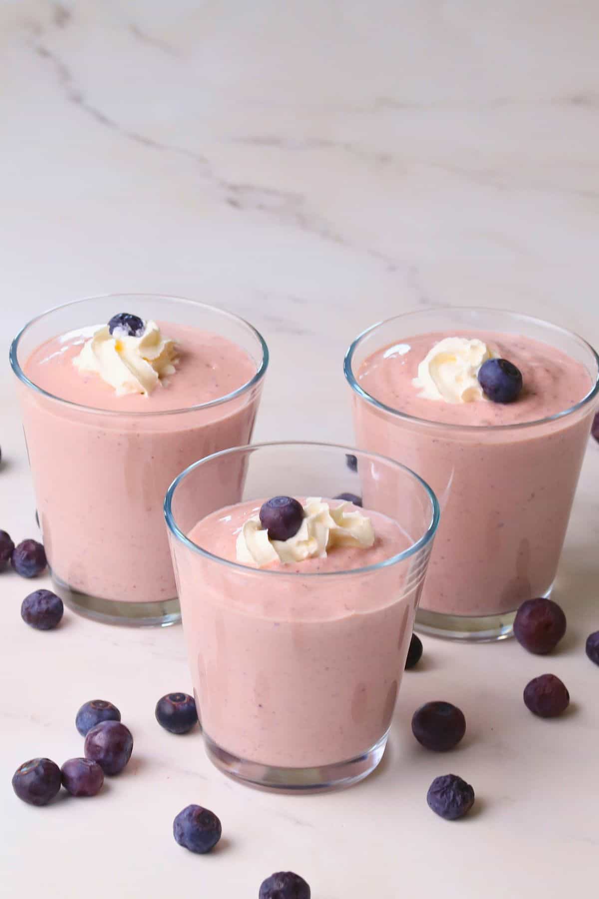 Low carb blueberry cottage cheese pudding in cups topped with whipped cream and blueberries.