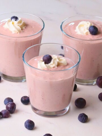 Low carb blueberry cottage cheese pudding in cups topped with whipped cream and blueberries.