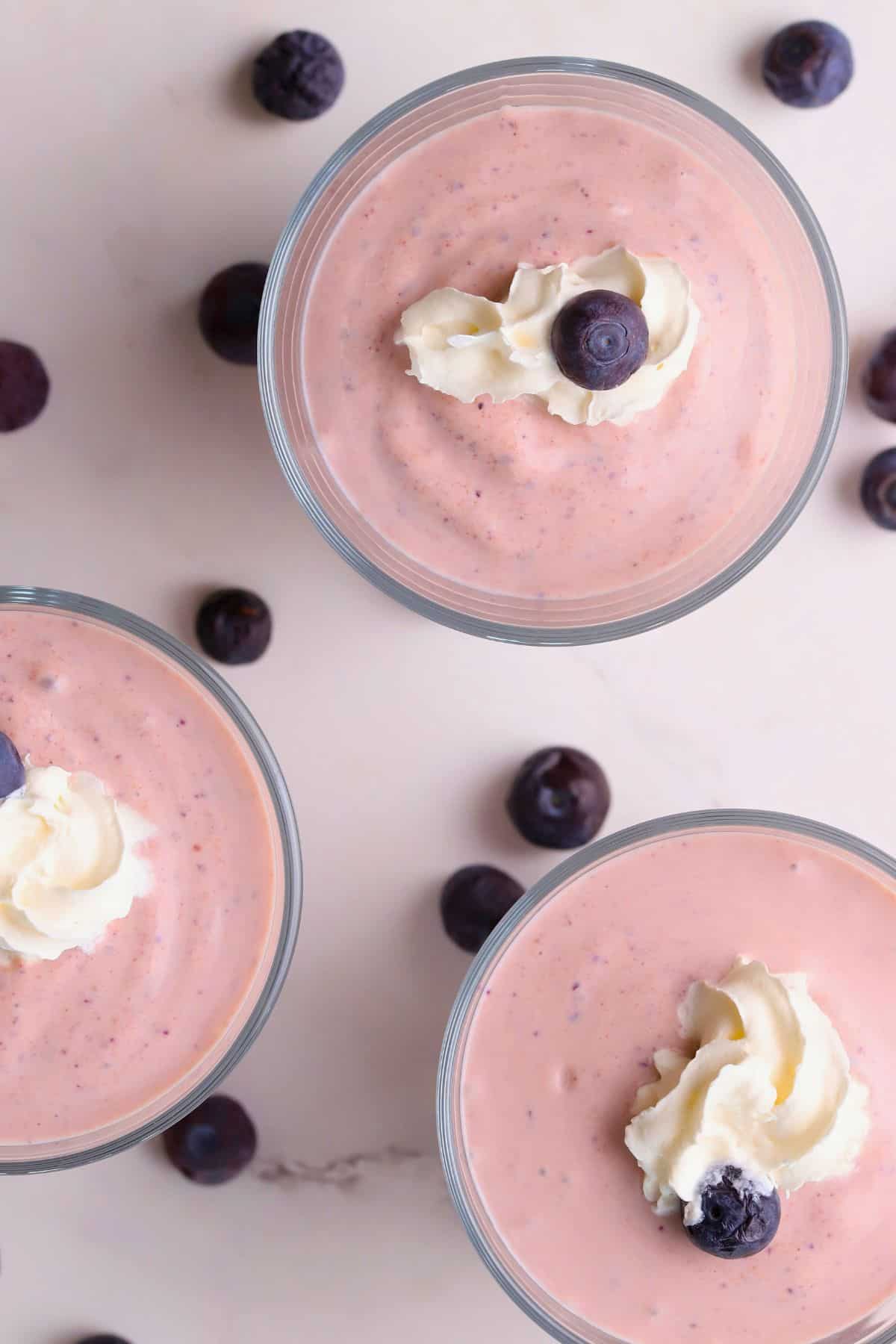 Low carb blueberry cottage cheese pudding in cups topped with whipped cream and blueberries.