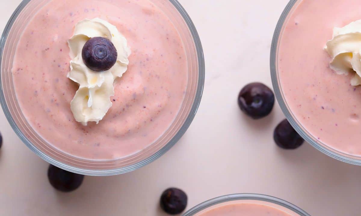 Low carb blueberry cottage cheese pudding in cups topped with whipped cream and blueberries.