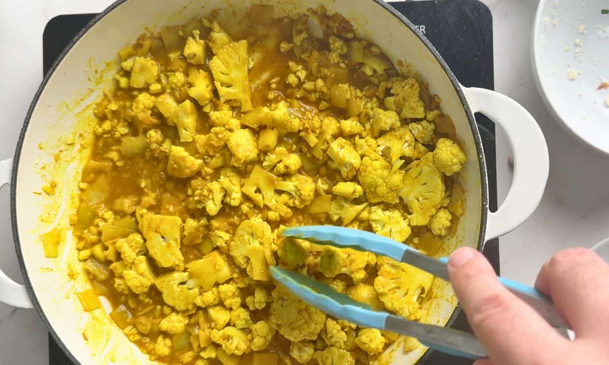 Stirring the cauliflower into the sauce.