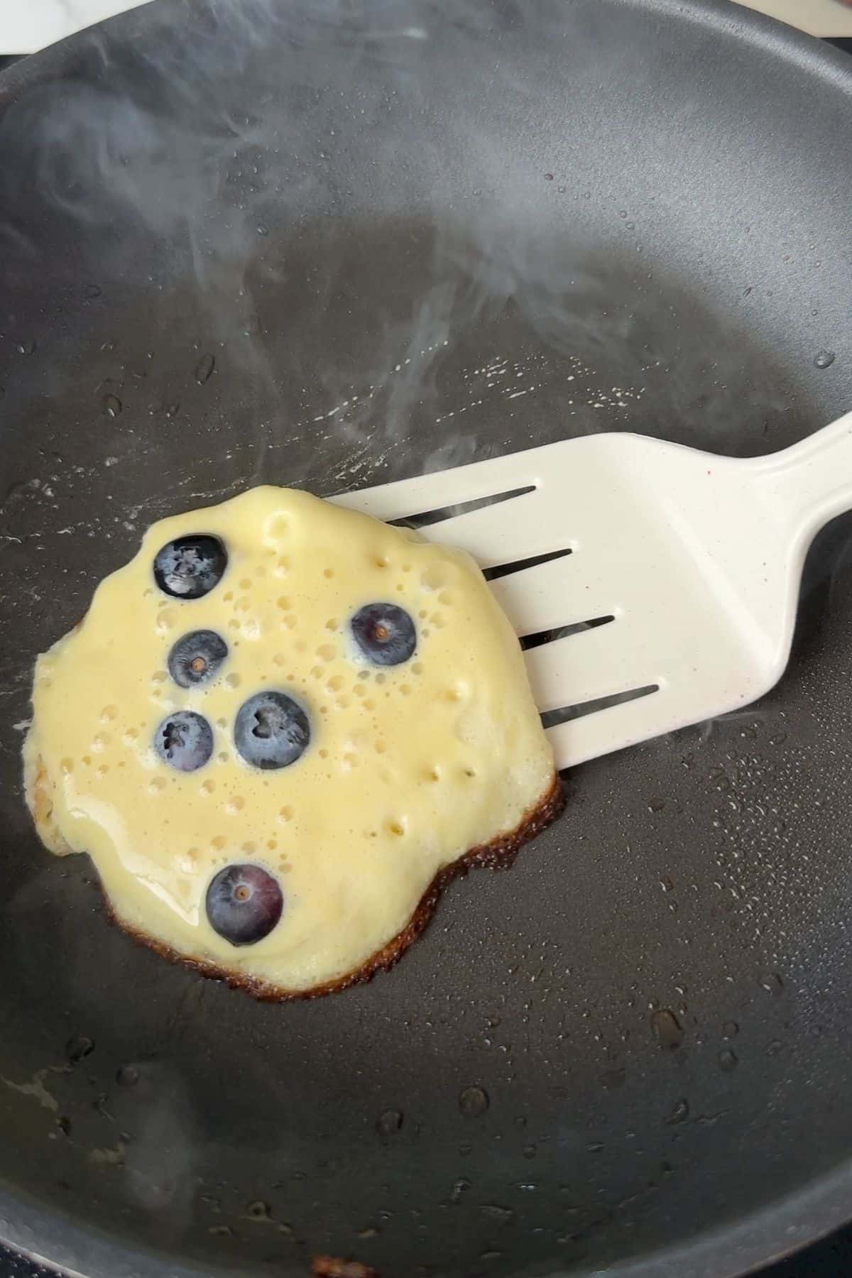 Flipping the blueberry cottage cheese pancake.