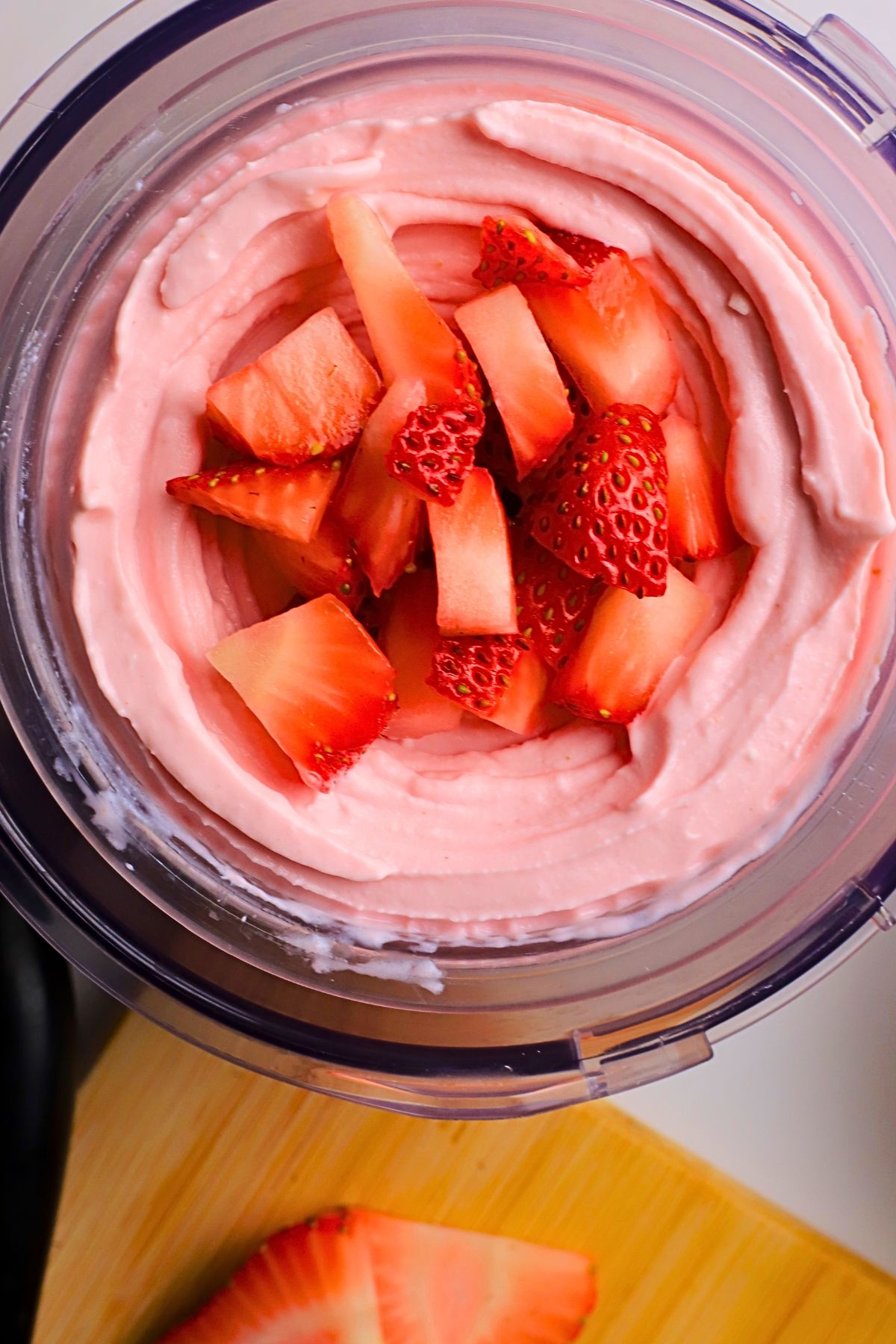 Low carb strawberry cottage cheese ice cream in a ninja creami pint topped with strawberries.