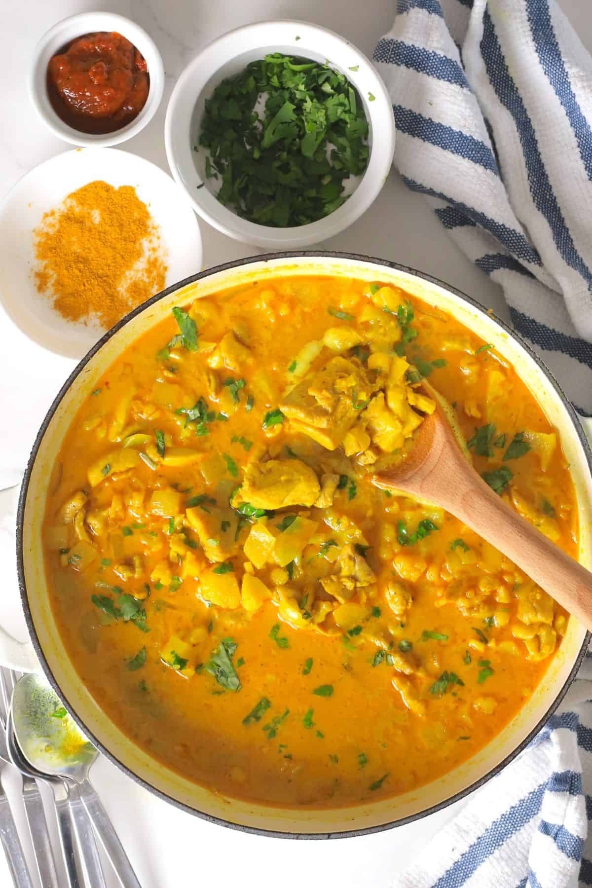 Spooning the low carb thai red curry chicken out of the skillet.