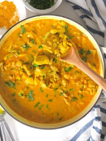 Spooning the low carb thai red curry chicken out of the skillet.