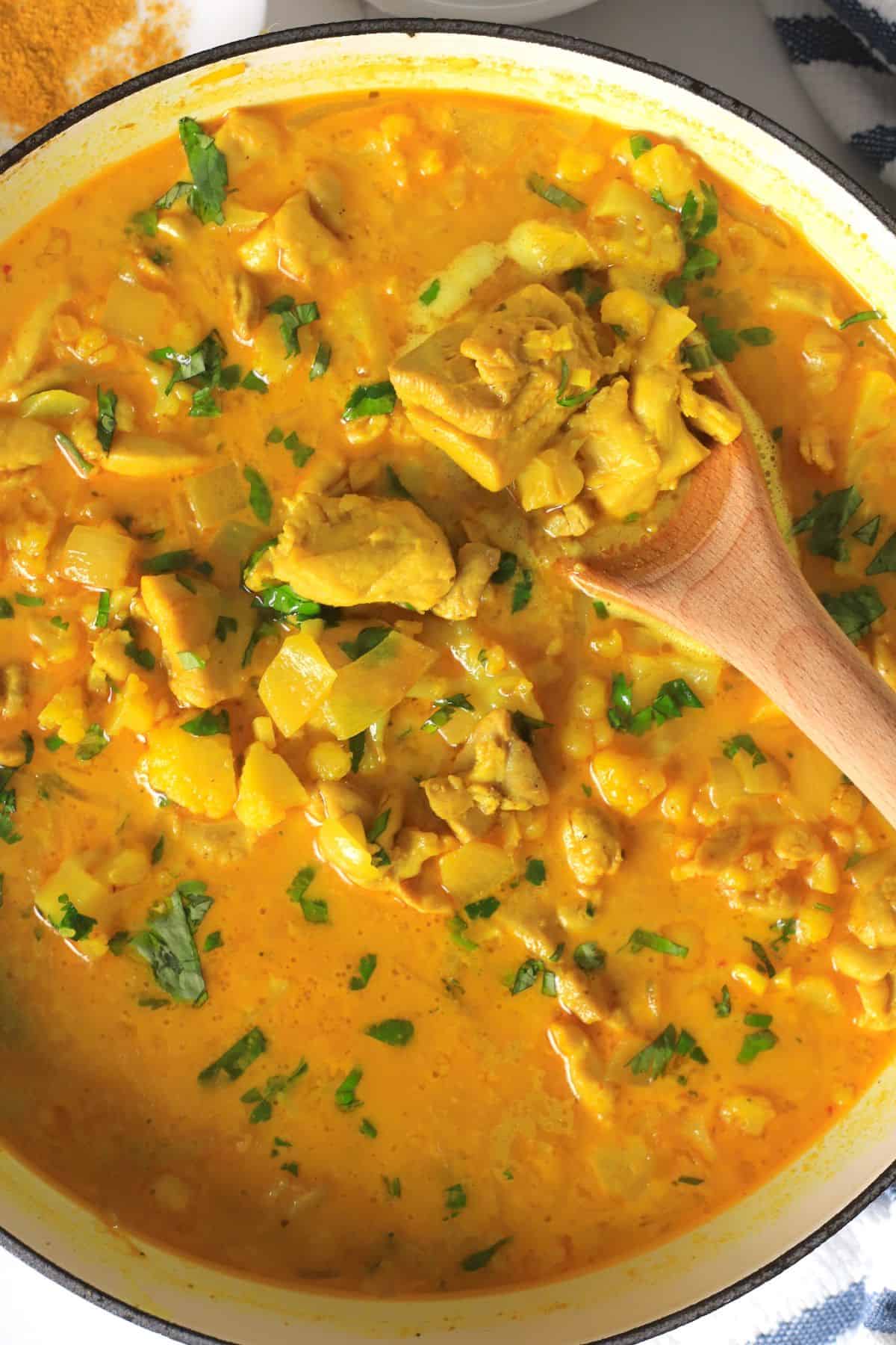 Spooning the low carb thai red curry chicken out of the skillet.