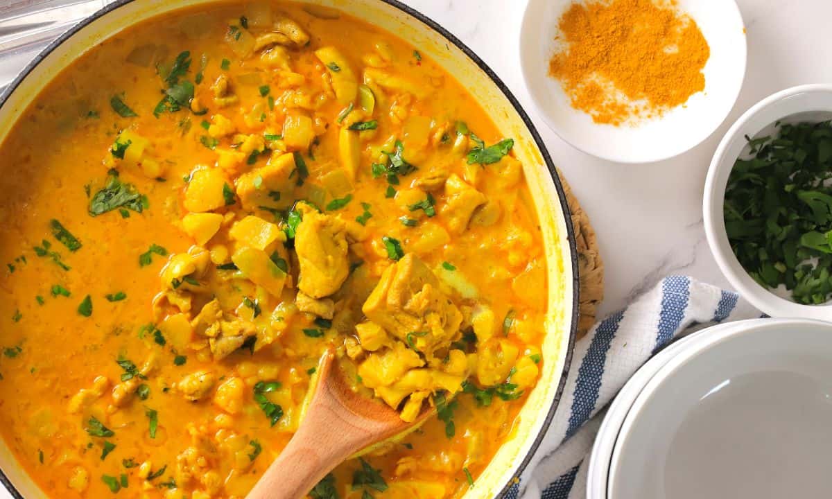 Spooning the low carb thai red curry chicken out of the skillet.