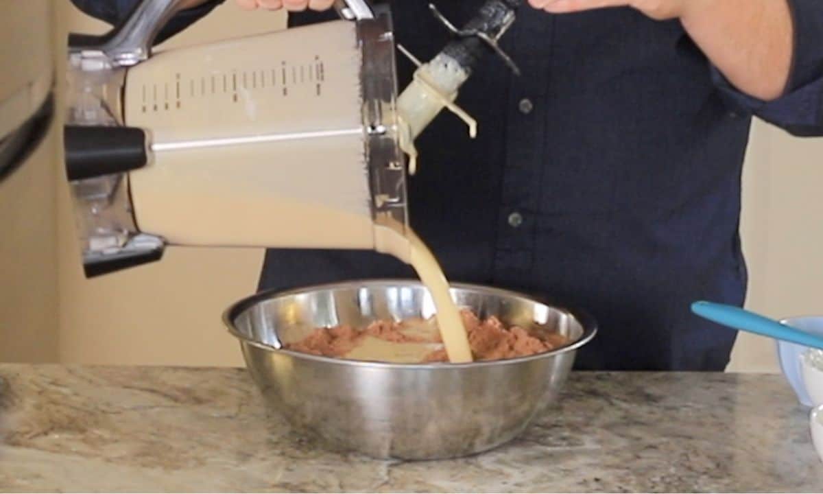 Pouring the wet ingredients from the blender into the bowl with the dry ingredients.