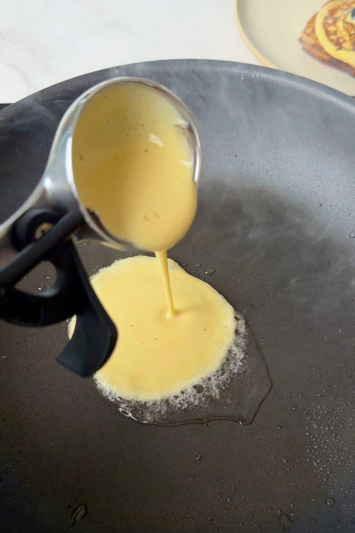 Pouring batter into a frying pan.