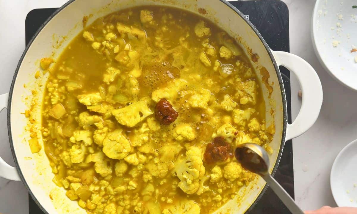 Adding the red curry paste to the sauce.