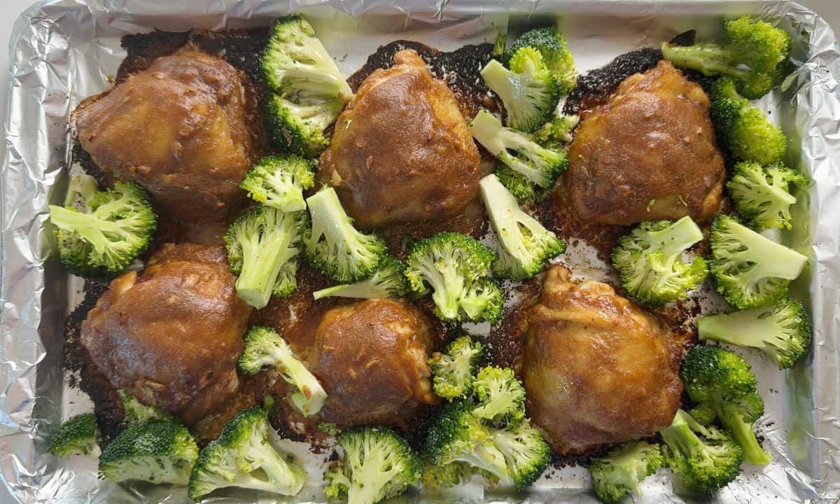 Sheet pan with chicken and fresh broccoli.