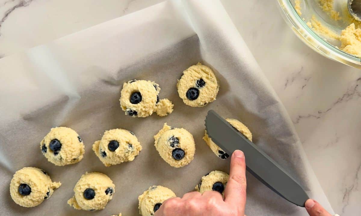 Flattening the cookies on the parchment lined baking tray.