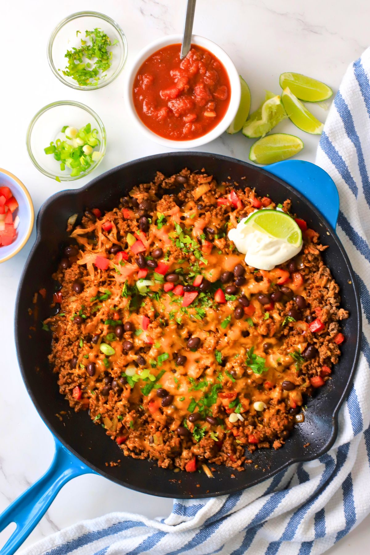 Flatlay shot of the Low carb taco skillet topped with cheese, sour cream and garnished with cilantro and green onions.