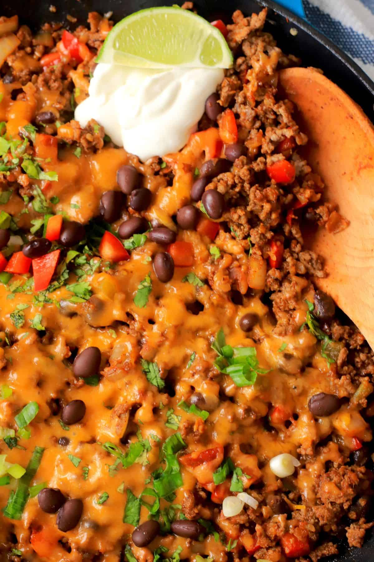 Close up shot of the Low carb taco skillet topped with cheese, sour cream and garnished with cilantro and green onions..