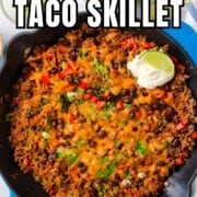 Pinterest image of the Low carb taco skillet topped with cheese, sour cream and garnished with cilantro and green onions.