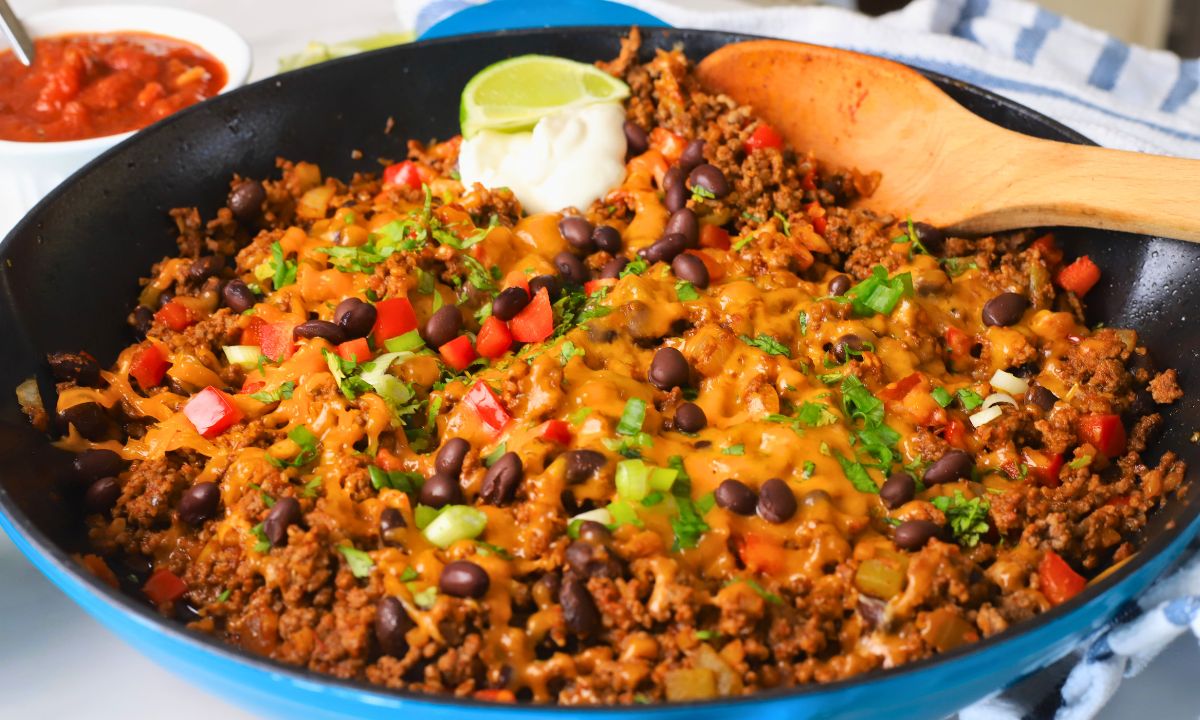 Wide shot of the Low carb taco skillet topped with cheese, sour cream and garnished with cilantro and green onions.
