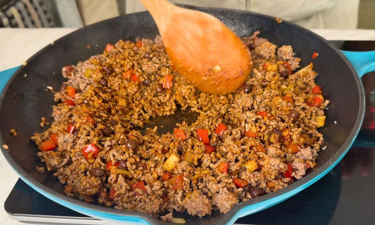 Stirring the ground beef in the skillet.