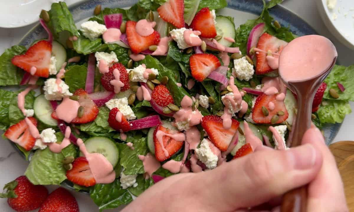 Spooning the homemade strawberry dressing over the salad.