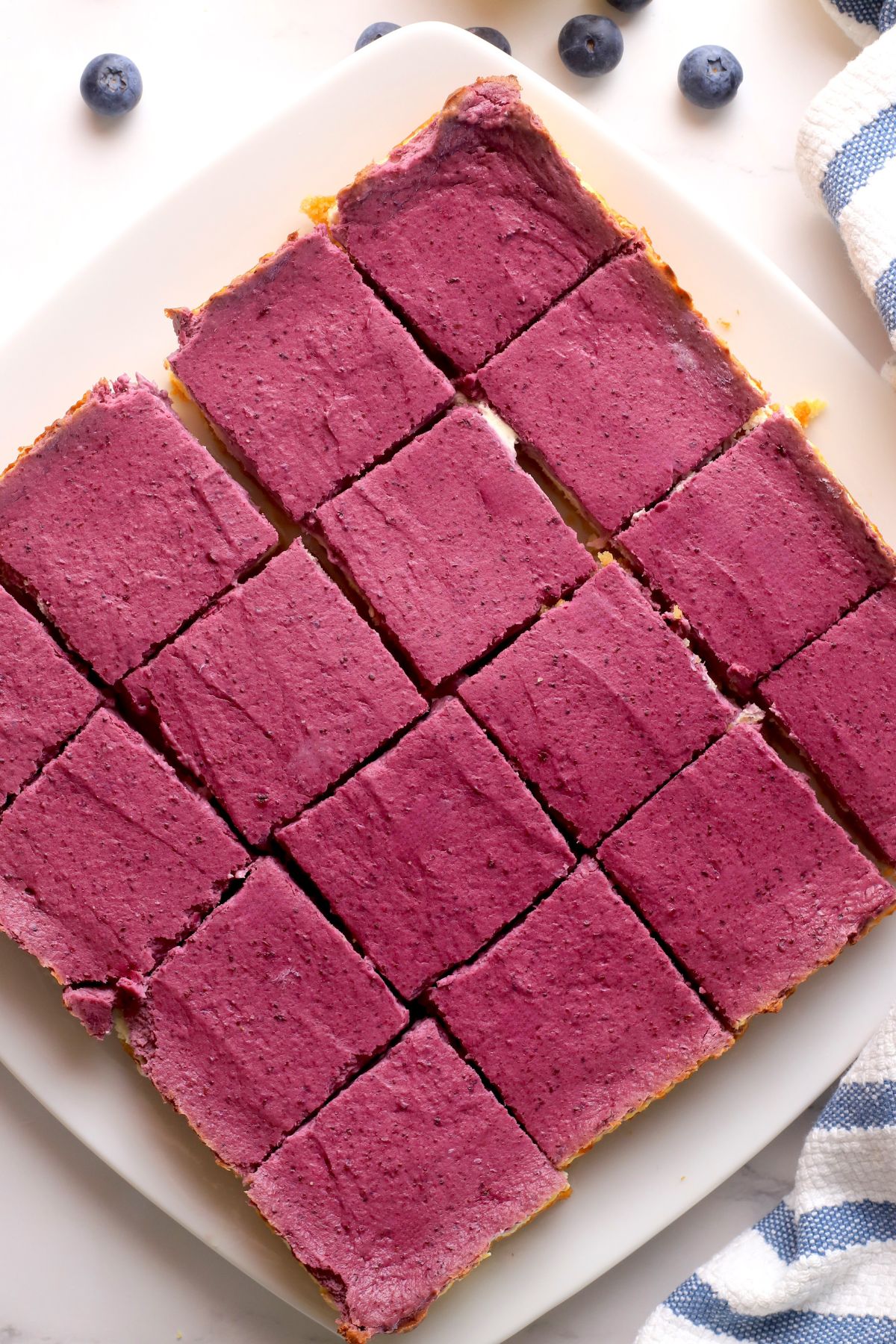 Low carb lemon blueberry cheesecake bars cut into squares on a plate.