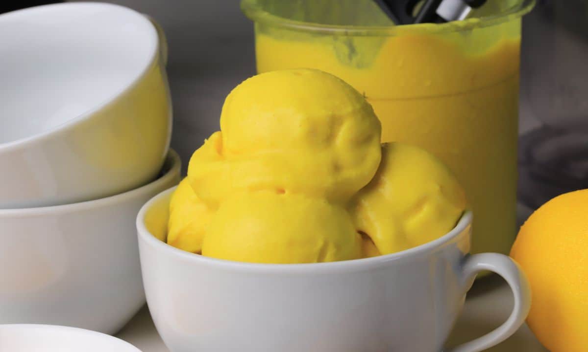 Low carb lemon turmeric ice cream in a bowl next to a lemon.