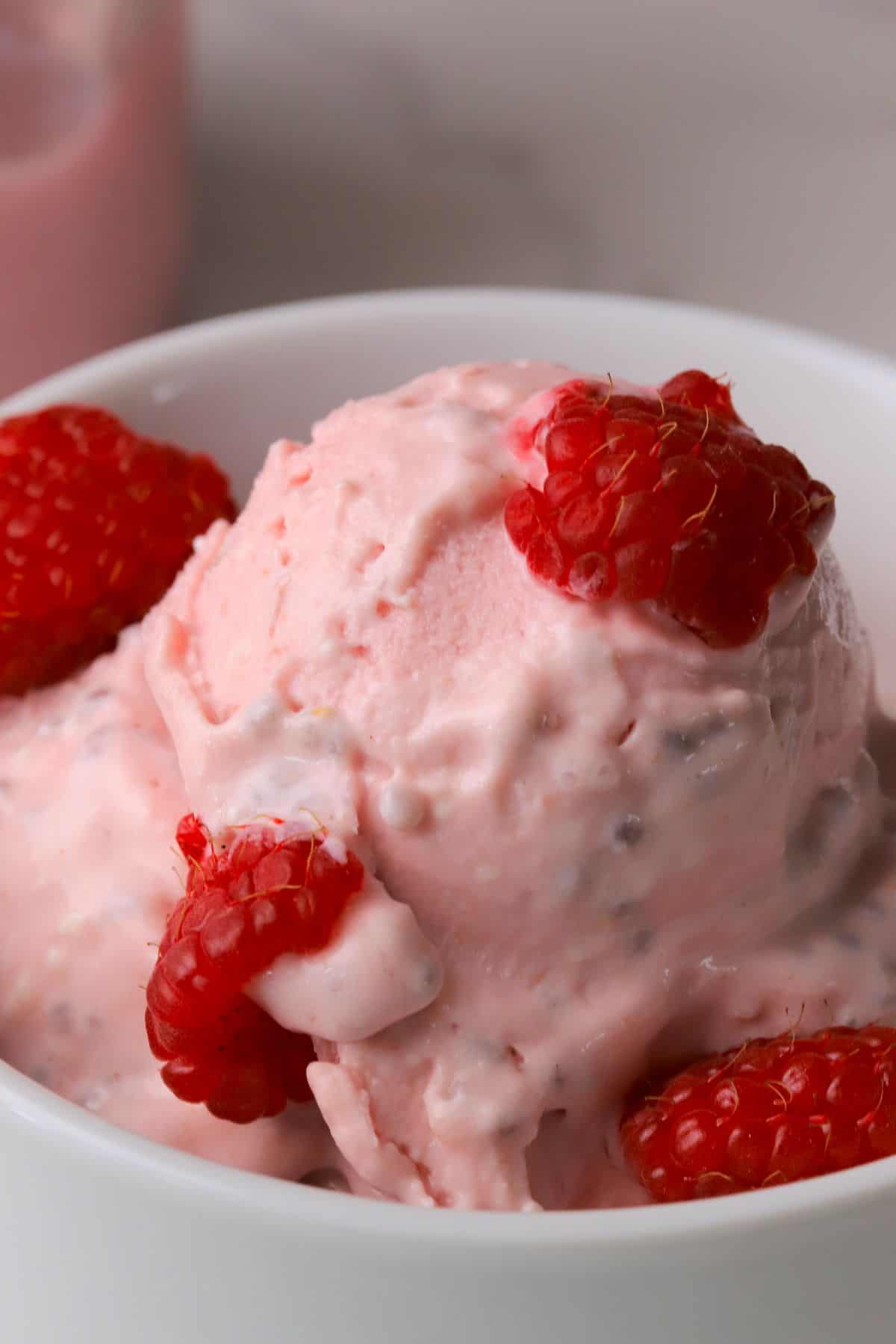 Low carb raspberry chia cottage cheese ice cream in a bowl topped with fresh raspberries.