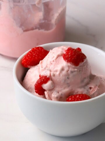 Low carb raspberry chia cottage cheese ice cream in a bowl topped with fresh raspberries.